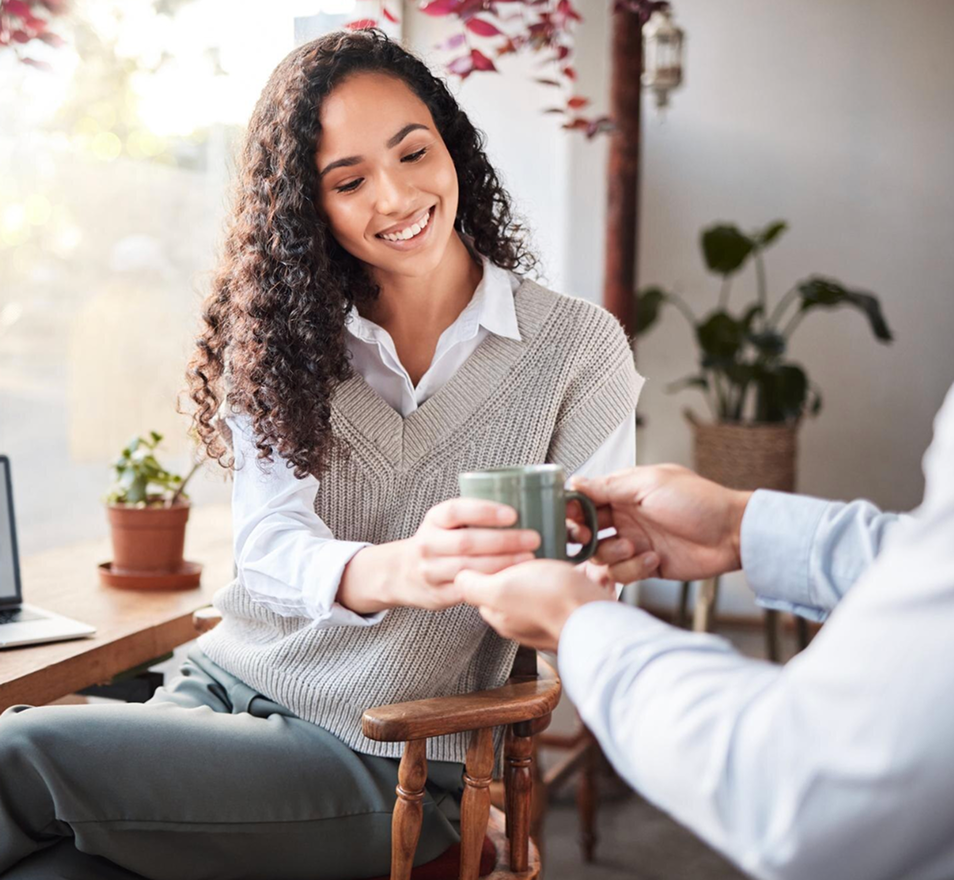 Profissional sorrindo ao receber uma xícara em uma conversa genuína, representando a escuta atenta e as relações de confiança que a Thesera Consultoria de RH constrói.